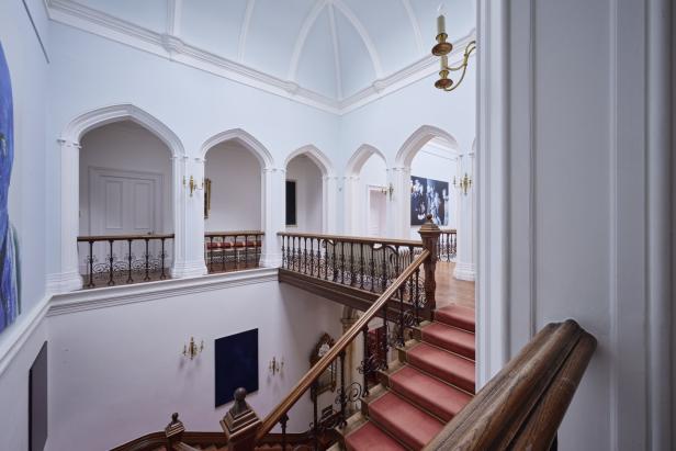 Ein Treppenhaus mit rotem Teppich und verzierten Geländern in einem hellen Gebäude.