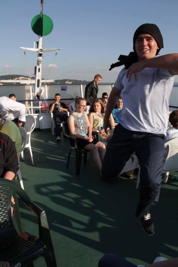 Ein junger Mann springt auf dem Deck eines Schiffes in die Luft.