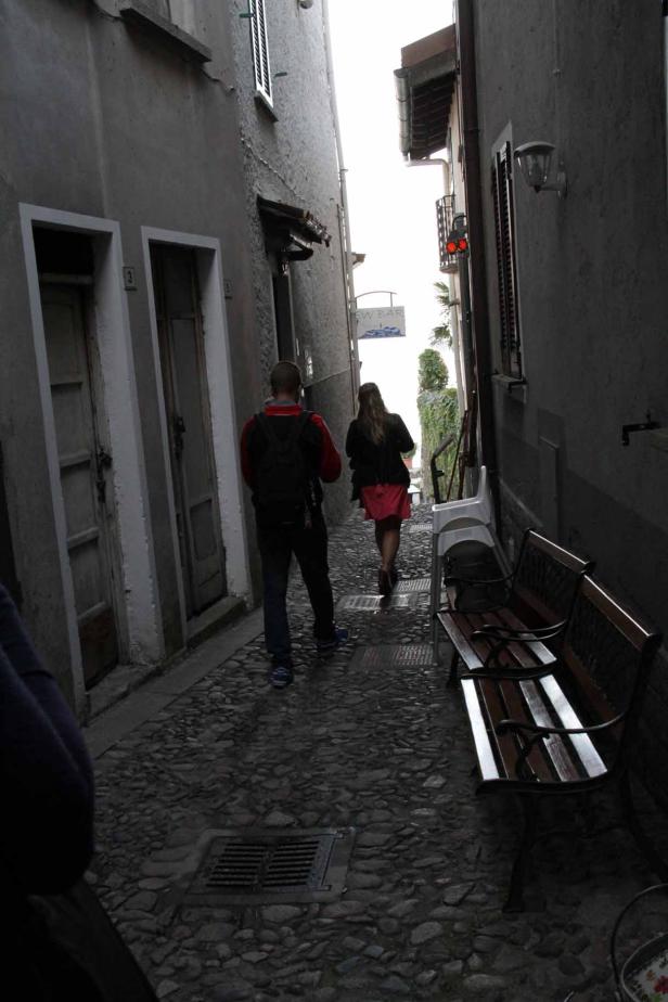 Ein Paar geht eine enge Gasse mit Kopfsteinpflaster entlang.