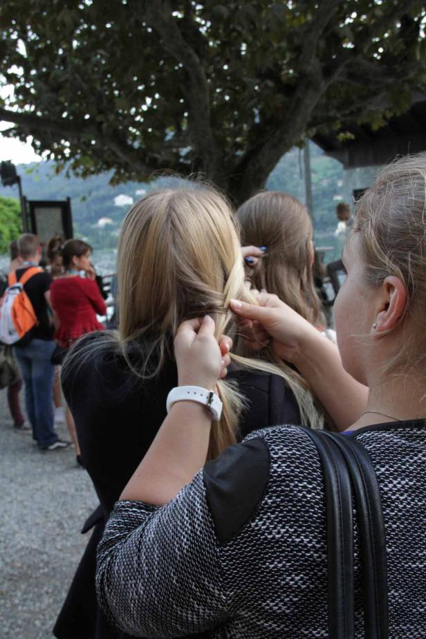 Eine Frau flechtet einer anderen Frau im Freien die Haare.