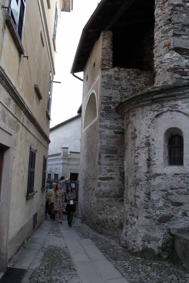 Eine Gruppe von Menschen geht eine enge Gasse entlang, gesäumt von alten Steingebäuden.