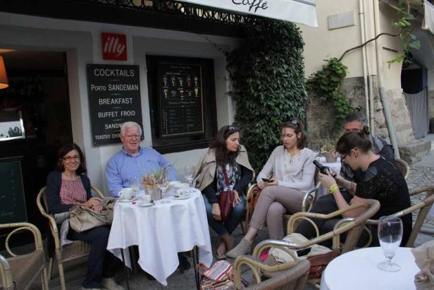 Eine Gruppe von Menschen sitzt an Tischen vor einem Café.