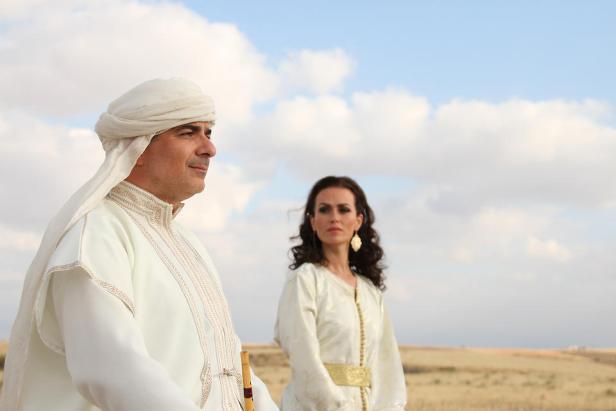 Ein Mann mit Turban und eine Frau in traditioneller Kleidung stehen in einer trockenen Landschaft.