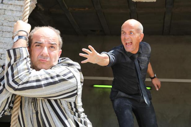 Ein Mann hält sich an einem Seil fest, während ein anderer Mann mit aufgerissenem Mund auf ihn zukommt.