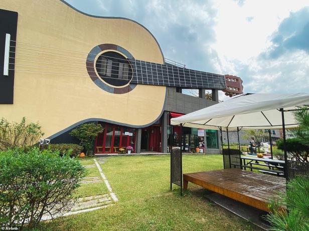 Ein Gebäude in Form einer riesigen Gitarre mit einem gepflegten Garten davor.