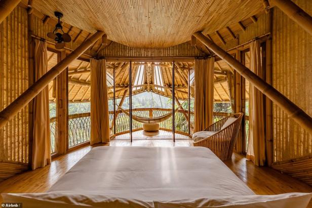 Ein Schlafzimmer in einem Bambushaus mit Blick auf die Natur.