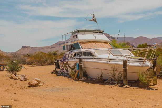 Ein ausrangiertes Boot steht mitten in einer Wüstenlandschaft.