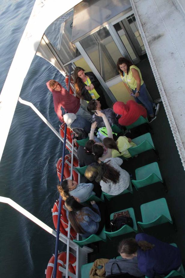 Eine Gruppe von Menschen sitzt auf einer Fähre und genießt die Aussicht.