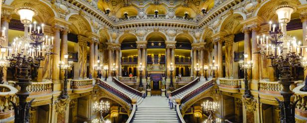 Die prunkvolle Treppe der Opéra Garnier in Paris mit Marmorsäulen und verzierten Geländern.