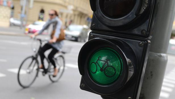 Eine Radfahrerin fährt an einer grünen Ampel für Fahrräder vorbei.