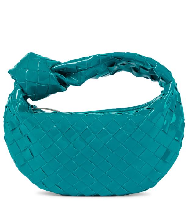 Eine türkisfarbene, gewebte Handtasche mit einem Knoten als Griff.