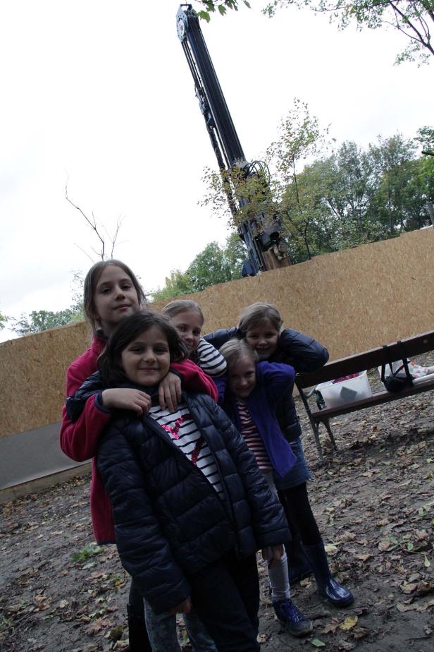 Fünf Mädchen stehen vor einer Holzwand und einem Baukran.