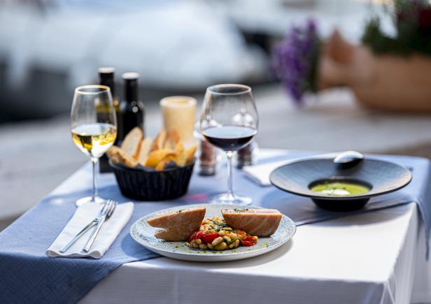 Ein gedeckter Tisch mit Thunfisch, Bohnensalat, Suppe, Brot und Wein.