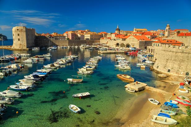 Blick auf den Hafen von Dubrovnik mit zahlreichen Booten und der historischen Stadtmauer.