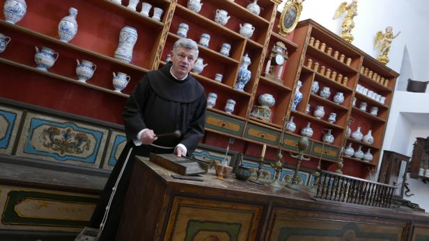Ein Mann in einer Apotheke aus dem 18. Jahrhundert mit alten Gefäßen und Geräten.