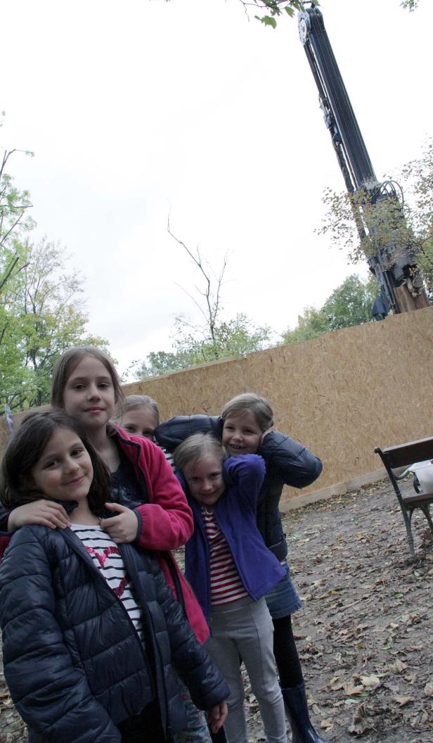 Eine Gruppe von fünf Mädchen posiert vor einer Baustelle mit einem Kran im Hintergrund.