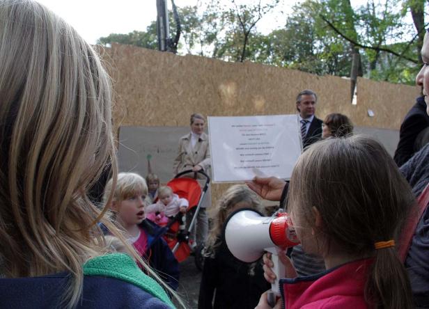 Kinder demonstrieren mit einem Megafon und einem Schild für den Erhalt von Bäumen.