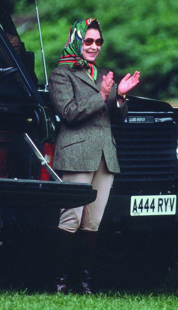 Königin Elisabeth II. klatscht vor einem schwarzen Land Rover.