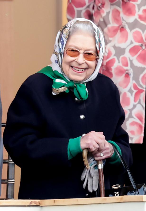Königin Elizabeth II. lächelt mit Kopftuch und Sonnenbrille.