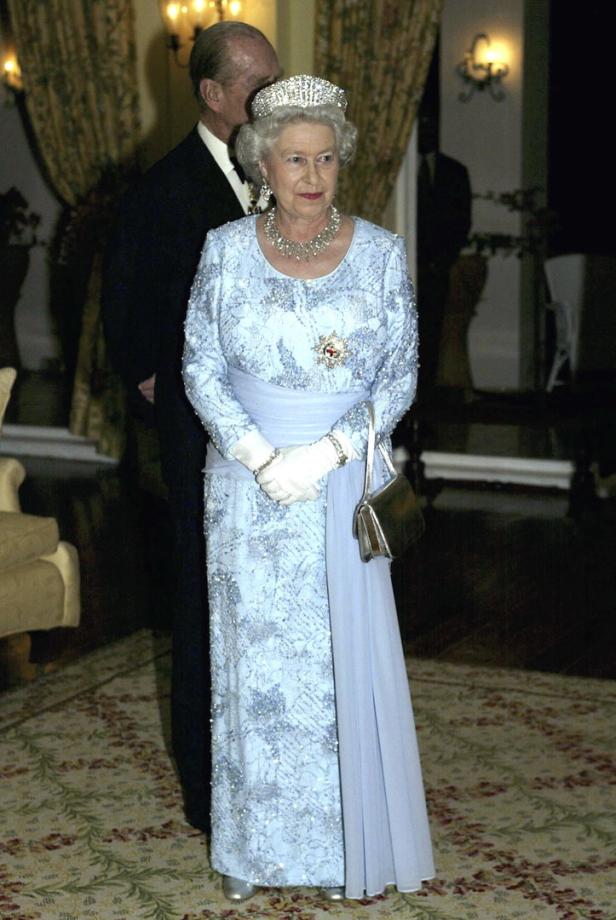 Königin Elisabeth II. mit Tiara und blauem Kleid, begleitet von Prinz Philip.