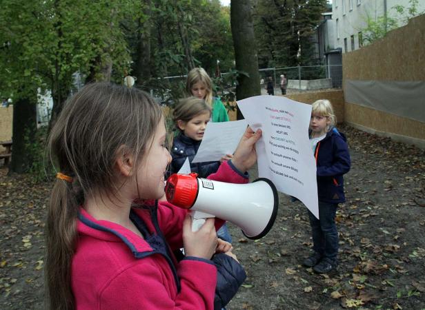 Eine Gruppe Kinder demonstriert mit einem Megafon und Plakaten im Freien.