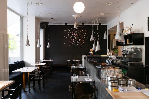 Innenansicht eines Restaurants mit Tischen, Stühlen und einer Bar.