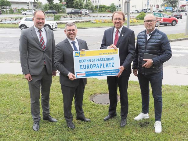 Vier Männer posieren mit einem Schild, das den Beginn des Straßenbaus am Europaplatz ankündigt.