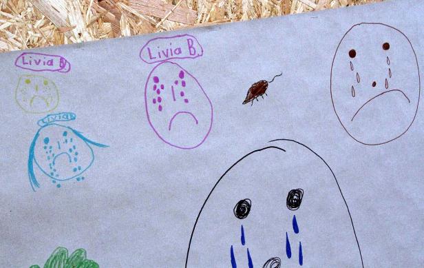 Eine Kinderzeichnung mit mehreren traurigen Gesichtern und der Aufschrift „Livia B.“.