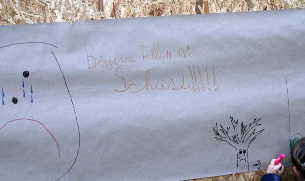 Ein Plakat mit der Aufschrift „Bäume fällen ist Scheiße!!!!“ und kindlichen Zeichnungen.