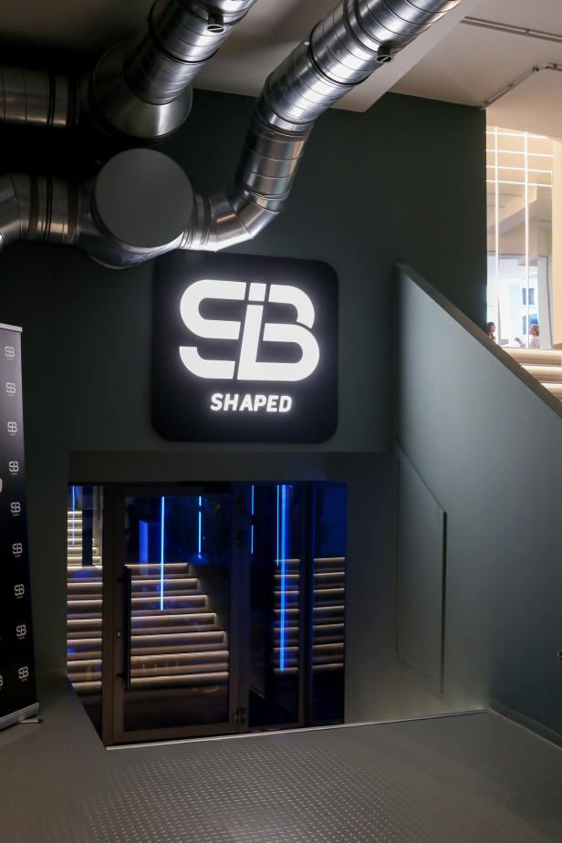 Ein Schild mit der Aufschrift „SB Shaped“ über dem Eingang zu einem Treppenhaus.