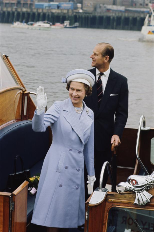 Königin Elisabeth II. und Prinz Philip auf einem Boot, die Königin winkt.