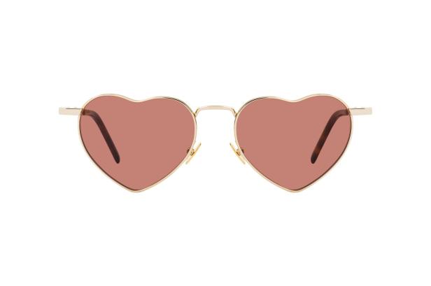 Eine herzförmige Sonnenbrille mit goldenem Rahmen und rosafarbenen Gläsern.