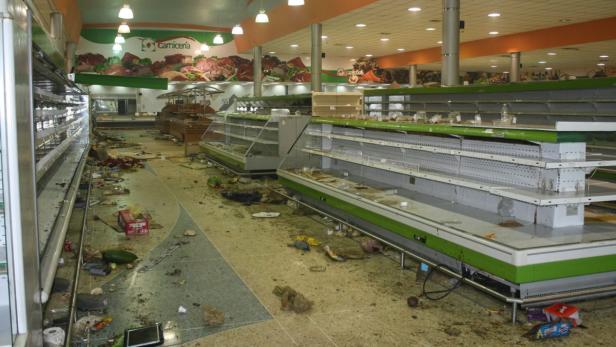 Ein verwüsteter Supermarkt mit leeren Regalen und Trümmern auf dem Boden.