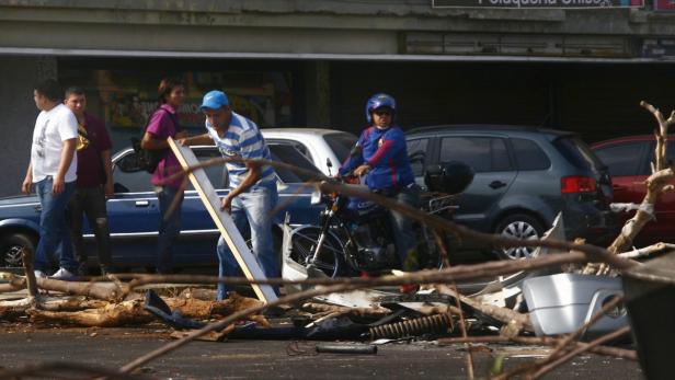 Eine Gruppe von Personen steht neben einem Motorrad und Trümmern auf der Straße.