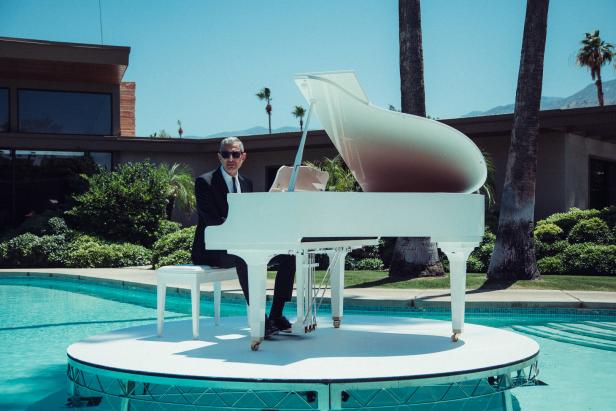 Jeff Goldblum sitzt am weißen Klavier auf einer Bühne im Pool.