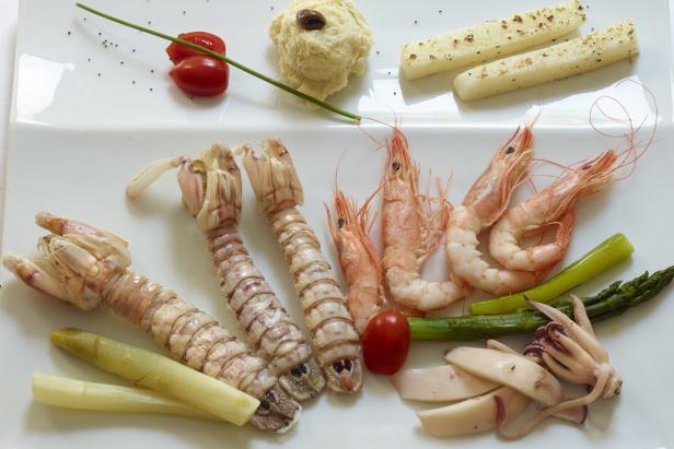 Eine Platte mit Meeresfrüchten, darunter Garnelen, Krebse und Tintenfisch, garniert mit Gemüse.