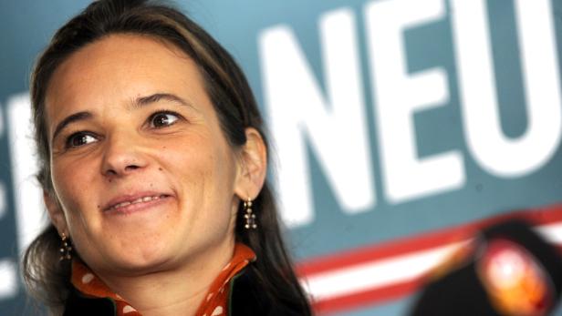 Eine Frau lächelt vor einem Hintergrund mit dem Wort „NEU“.