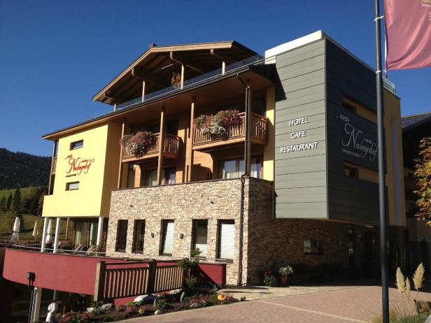 Das Hotel „Mein Neubergerhof“ mit Balkonen und Blumenkästen an einem sonnigen Tag.