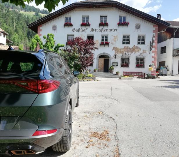 Ein grüner Cupra steht vor dem Gasthof Straßerwirt in den Bergen.