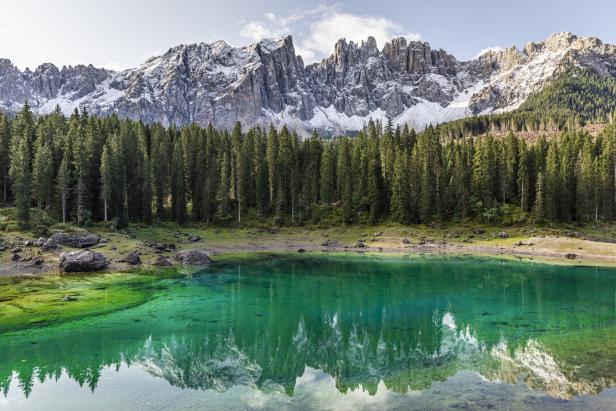 Der smaragdgrüne Karersee spiegelt die schneebedeckten Dolomiten wider.