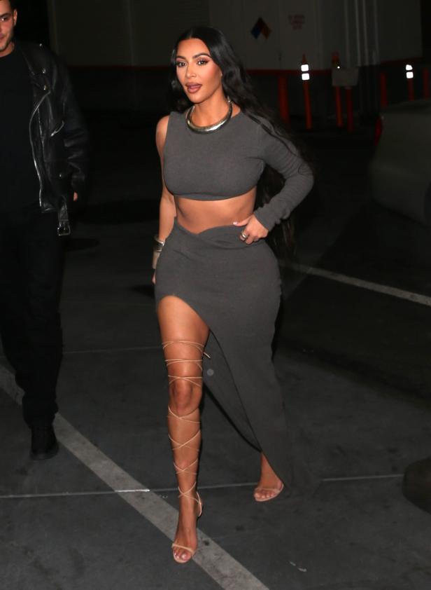 Kim Kardashian trägt ein graues zweiteiliges Outfit und Schnürschuhe.