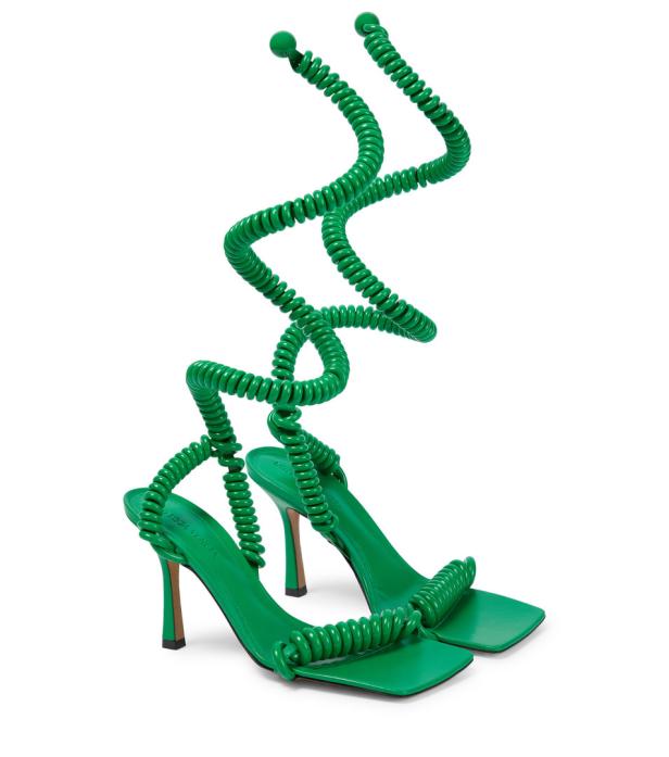 Ein Paar grüne High-Heel-Sandalen mit spiralförmigen Riemen winden sich um den Knöchel.