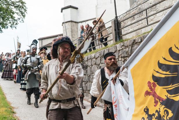 Eine Gruppe von Menschen in historischen Kostümen nimmt an einer Parade teil.