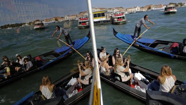 Gondolieri staken ihre Gondeln durch die Kanäle von Venedig, während Touristen die Fahrt genießen.