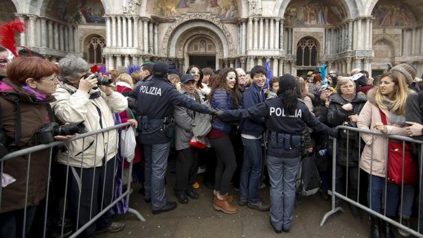 Polizisten kontrollieren eine Menschenmenge vor dem Markusdom in Venedig.