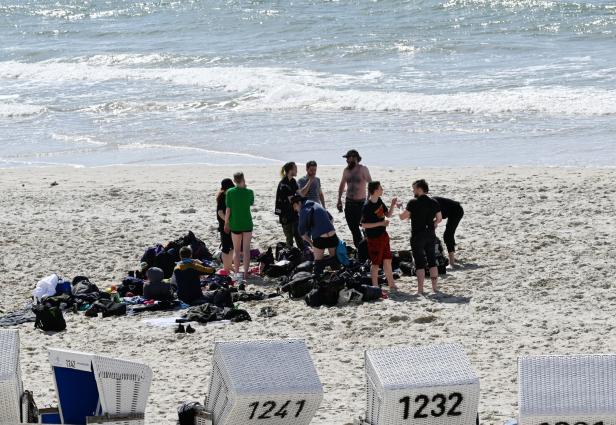 Eine Gruppe von Menschen steht am Strand neben ihren Rucksäcken.