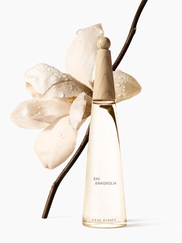 Eine Flasche „Eau & Magnolia“ von L'Eau d'Issey neben einer Magnolienblüte.