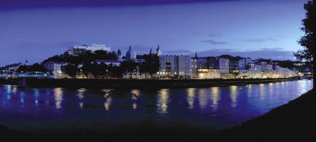 Panorama von Salzburg bei Nacht mit Festung Hohensalzburg und dem Salzach-Fluss.