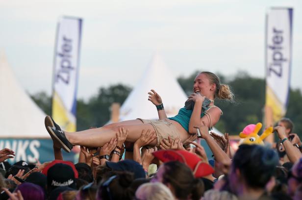Eine junge Frau wird auf einem Festival von einer Menschenmenge auf Händen getragen.