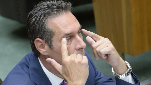 Ein Mann in einem Anzug berührt seine Augen mit den Fingern.